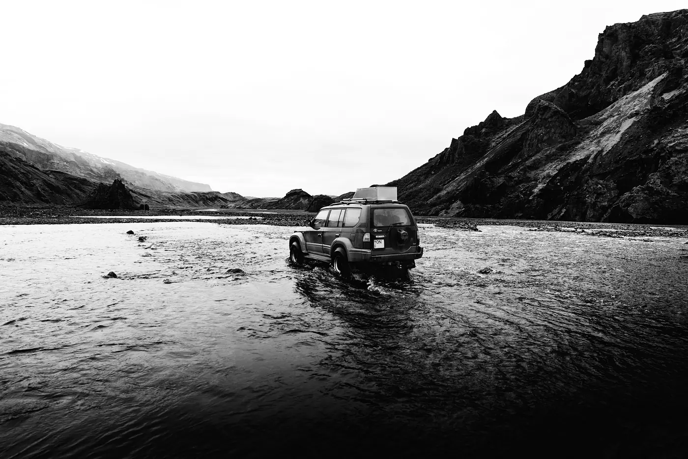 A 4x4 driving through a wide river in the Icelandic highlands